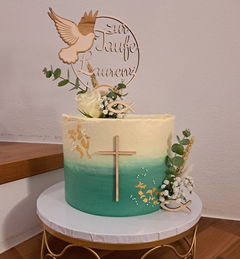 Tortenstecker aus Holz zur Taufe mit Taube und dem Schriftzug „zur Taufe Laurenz“ auf einer türkisen Torte mit Holzkreuz